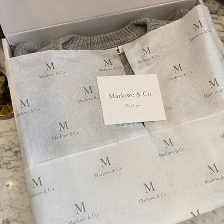 Custom tissue paper printed with a repeating brand logo wrapped around a boutique order